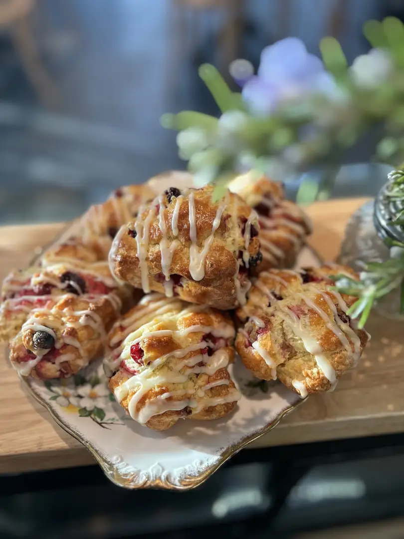 Freshly baked berry scones with icing drizzle.