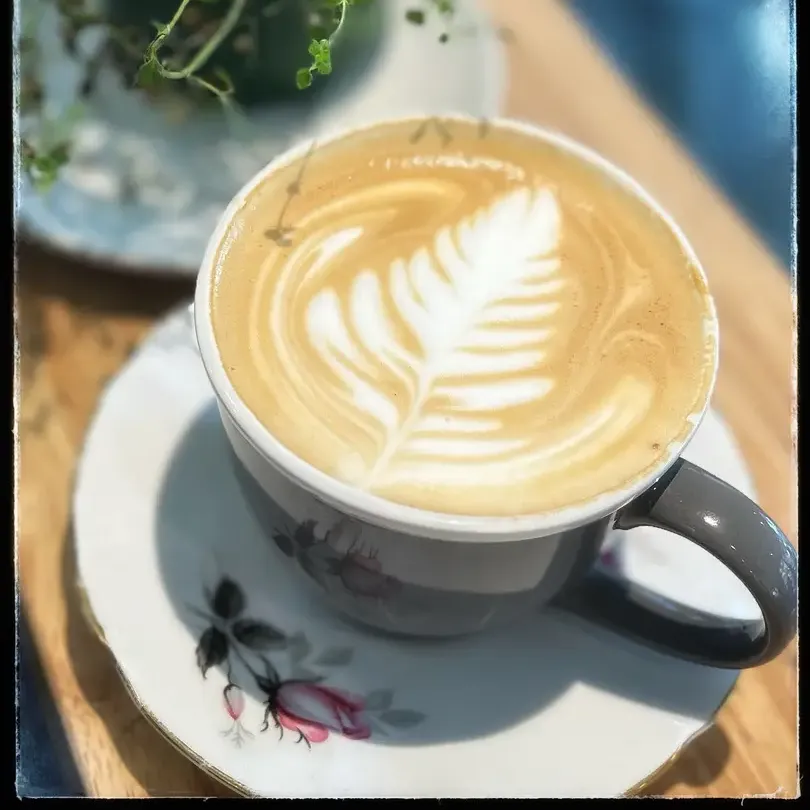 Latte art with a plant in the background.