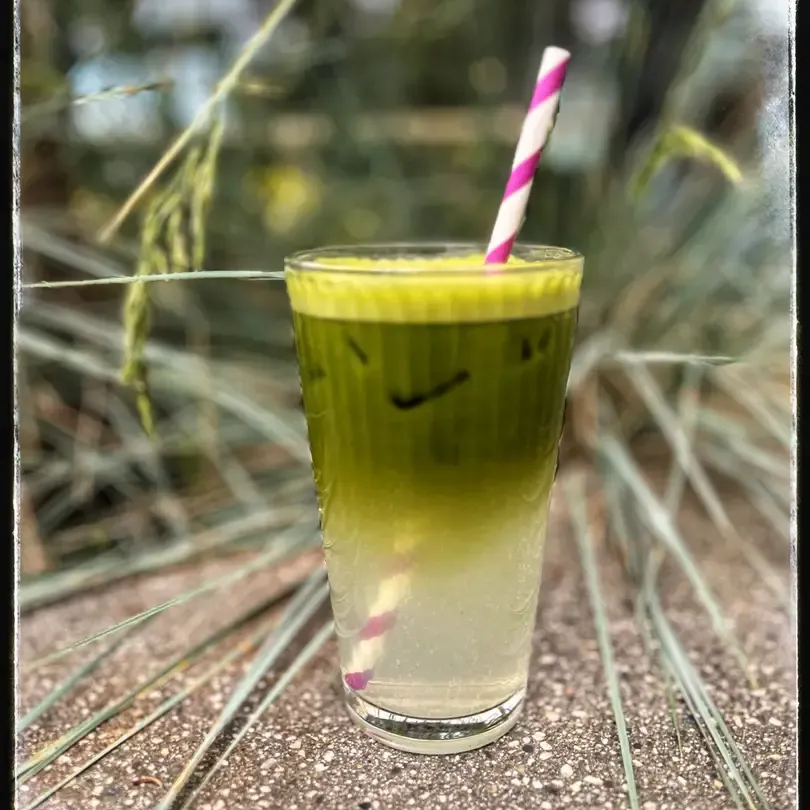 Matcha limeade drink with a straw.